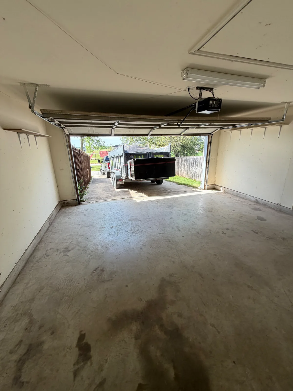 After photo of the same garage completely cleared out, with the loaded Kick It trailer parked outside