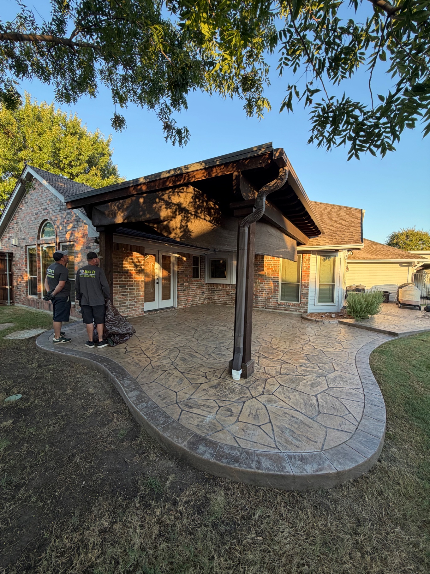 Attached wood pergola over the stamped concrete patio in Lewisville before demolition