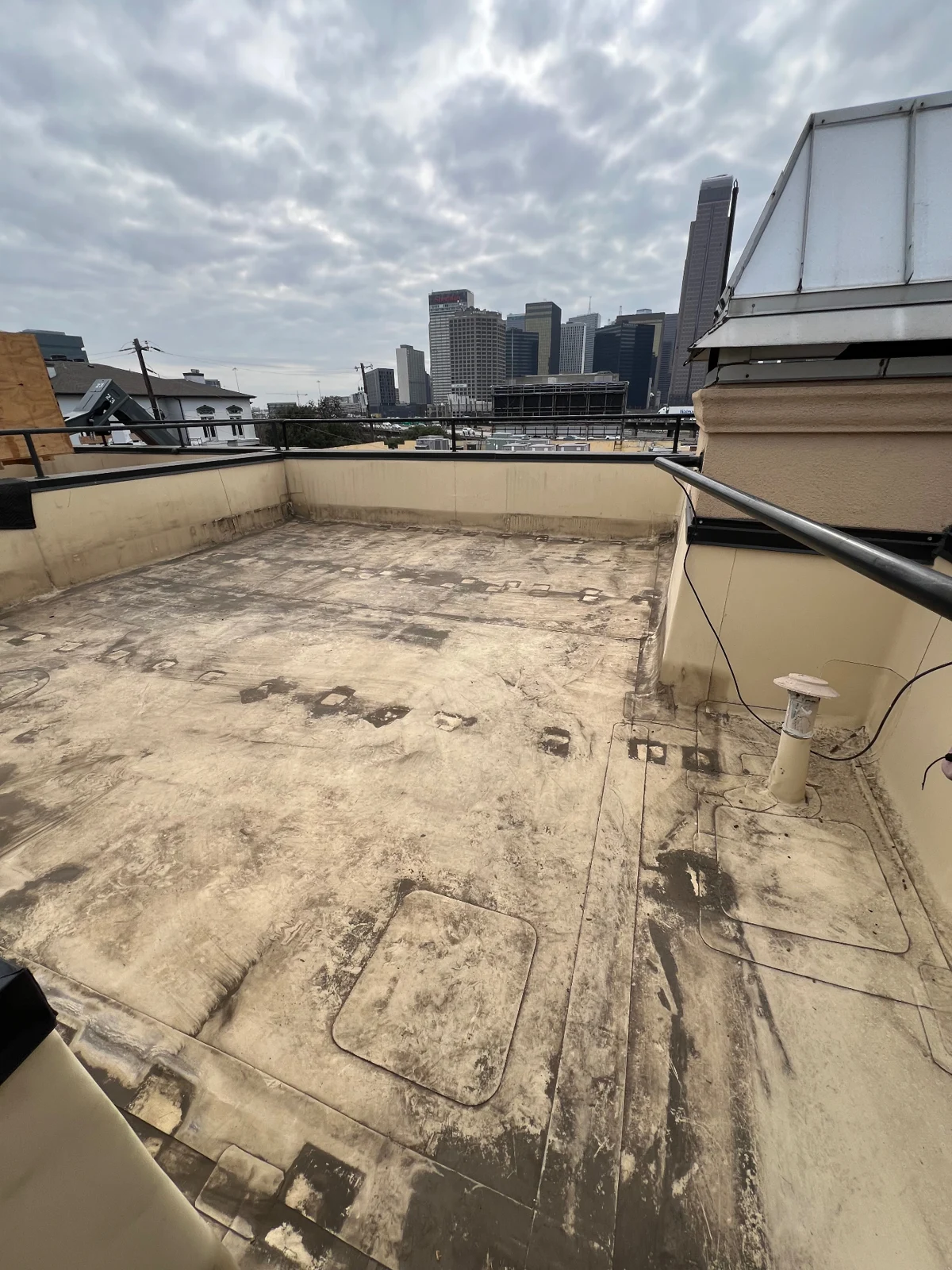 Dallas rooftop cleared after wood deck demolition with the downtown skyline visible
