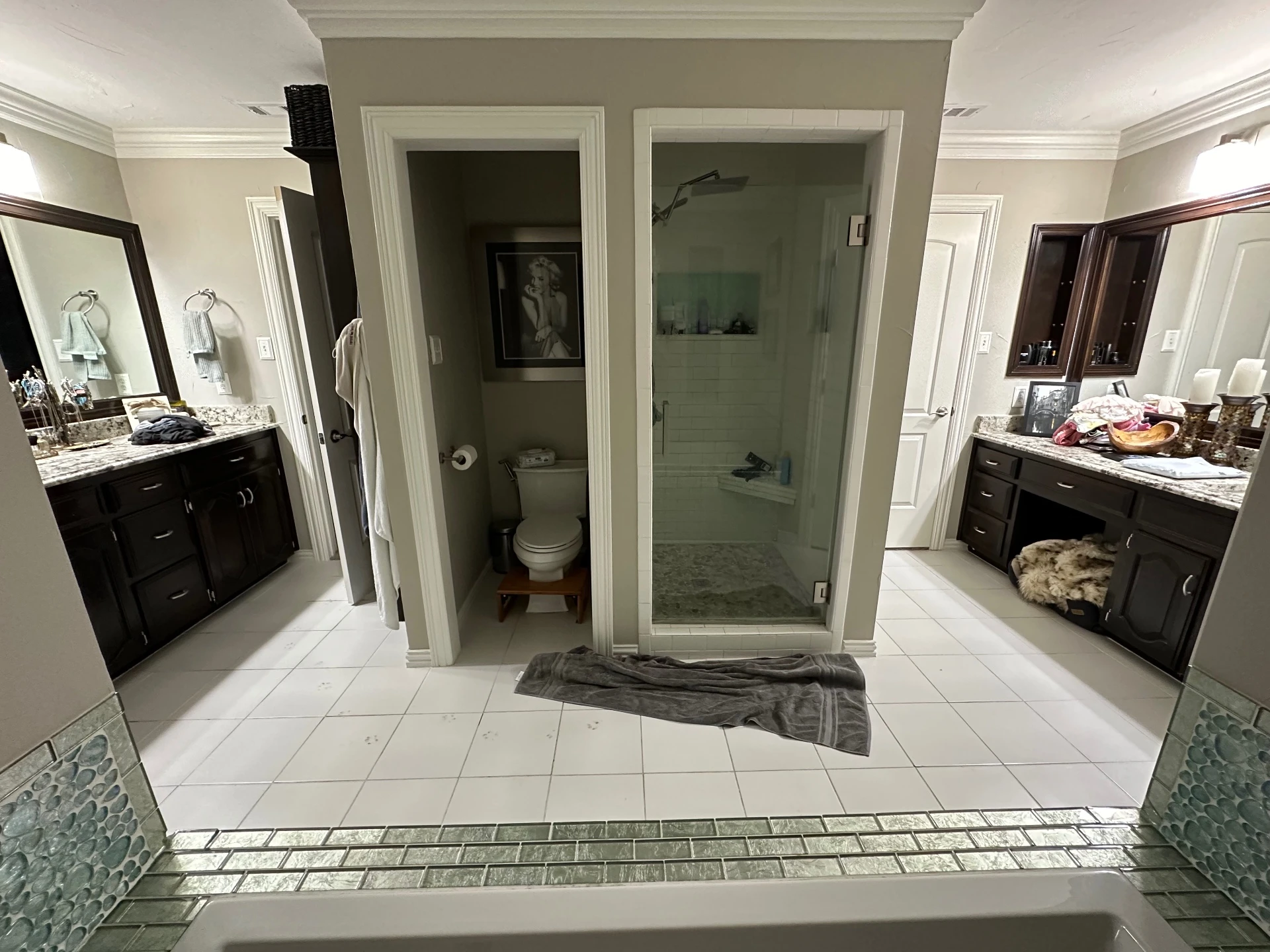 Master bathroom before remodel demolition with glass shower, toilet and dark wood vanities intact