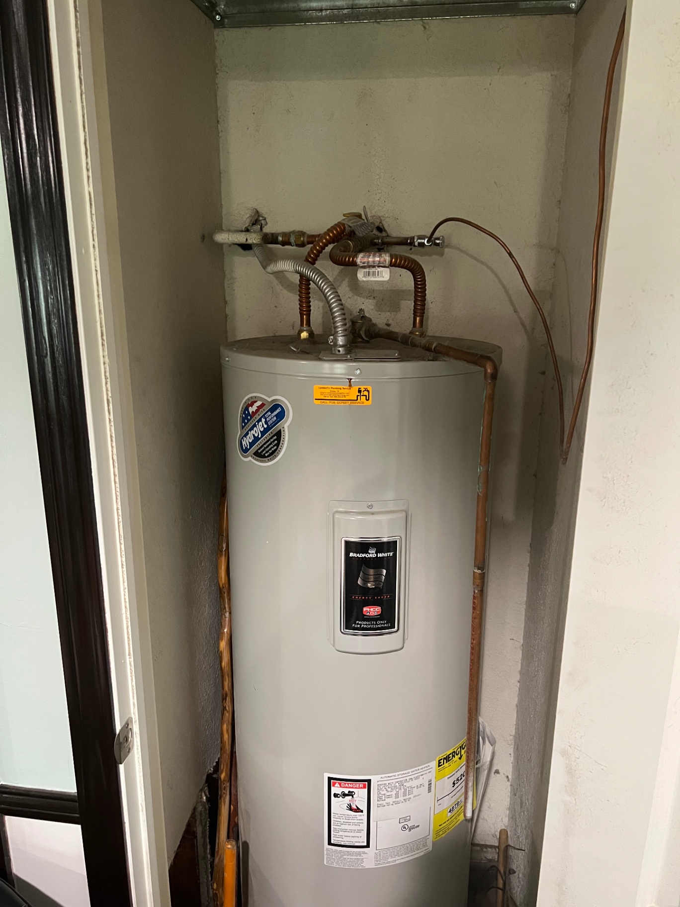 Residential tank-style water heater in a narrow utility closet before removal