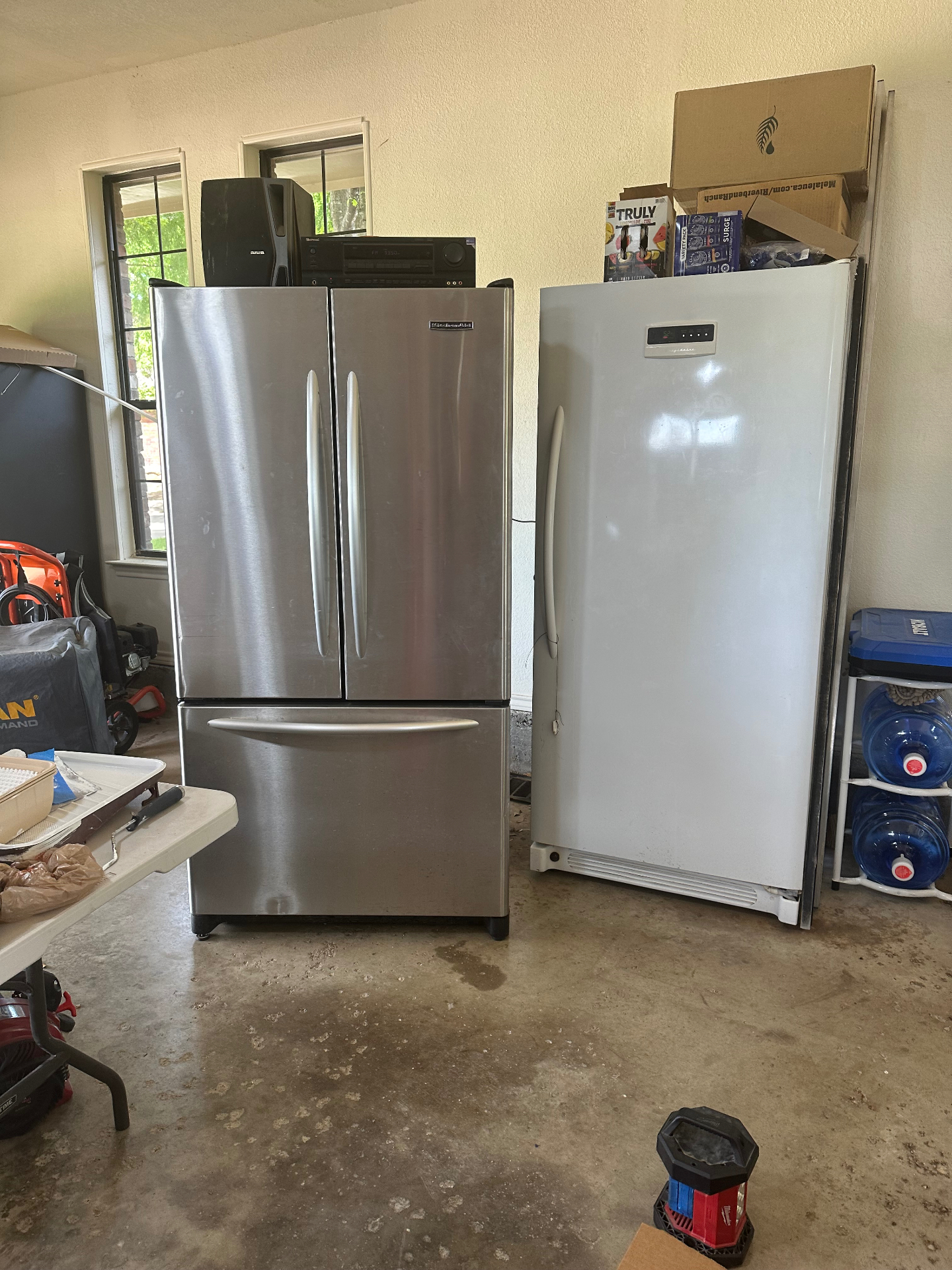 Two refrigerators waiting in a garage for pickup