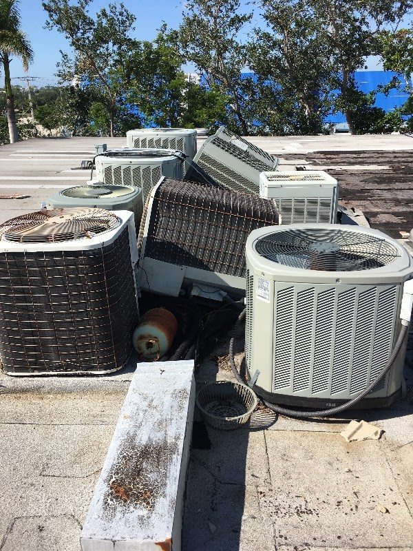 Multiple removed AC condenser units staged together for haul-away