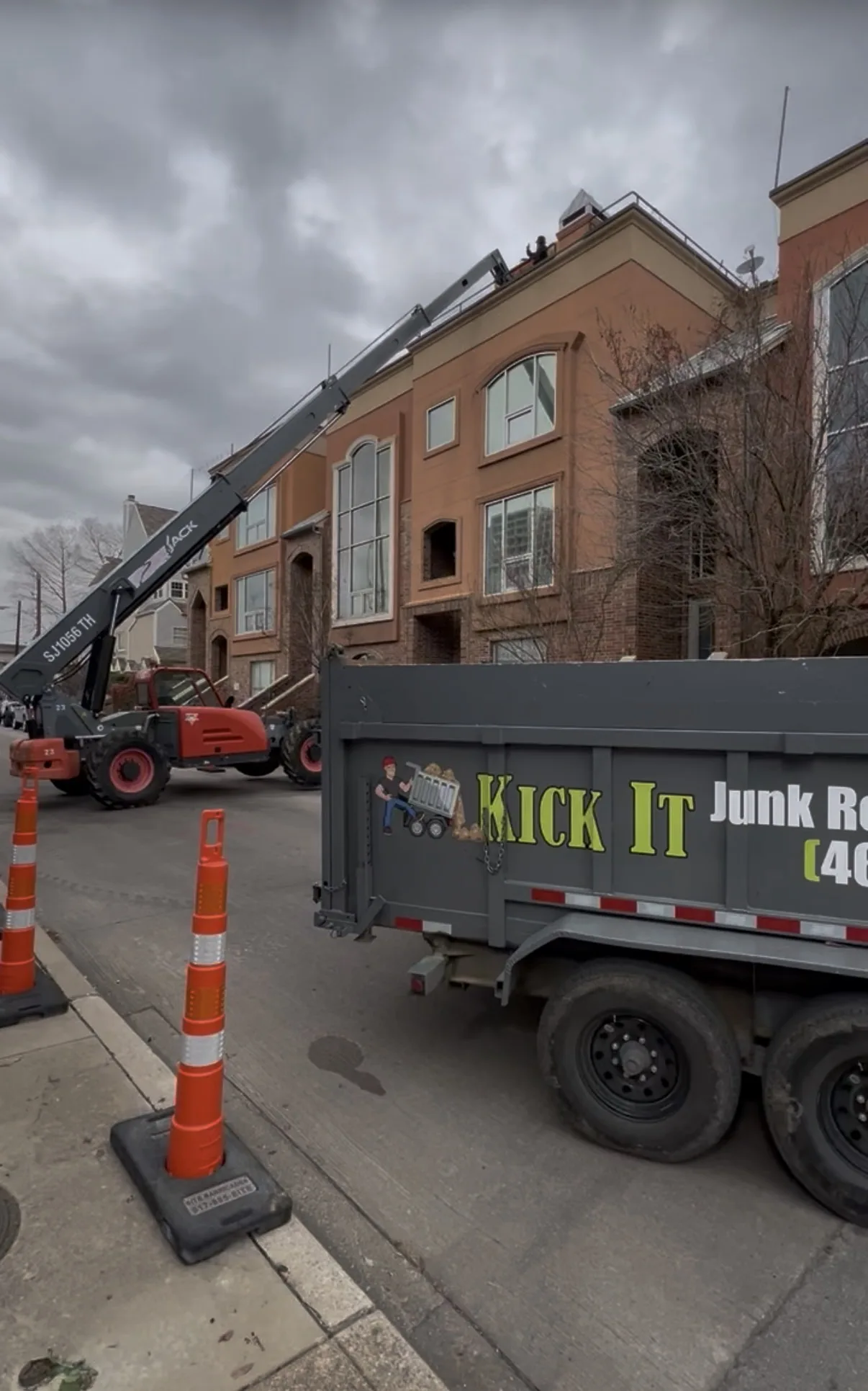Crane lifting rooftop deck debris down to the Kick It dump trailer