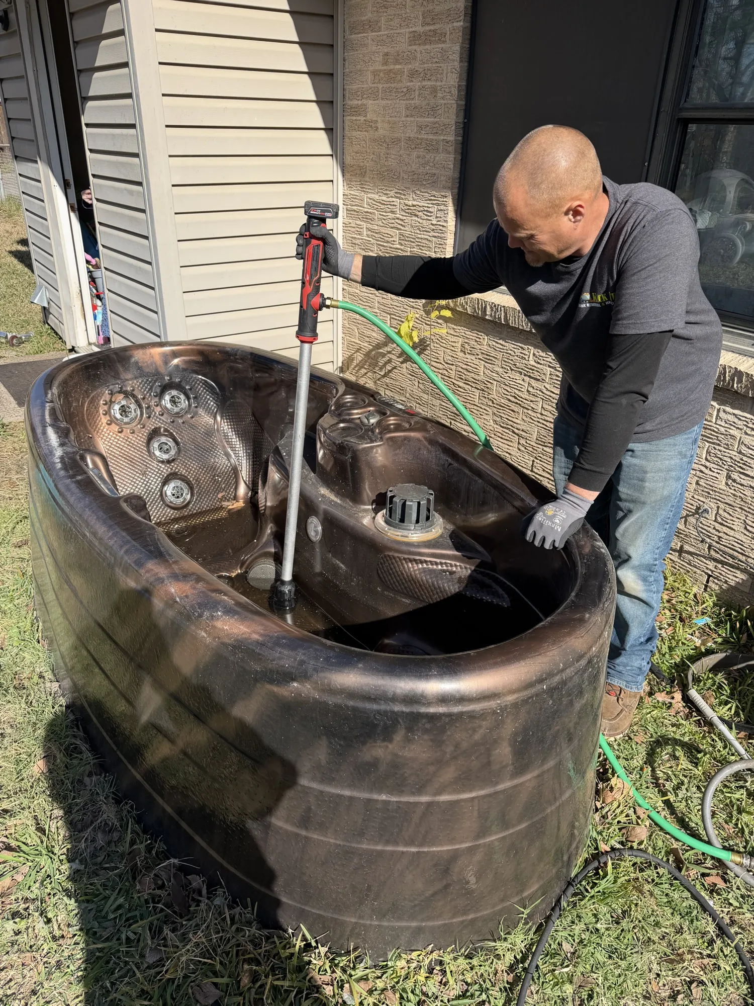 Kick It crew member dismantling a hot tub shell during a difficult-access removal