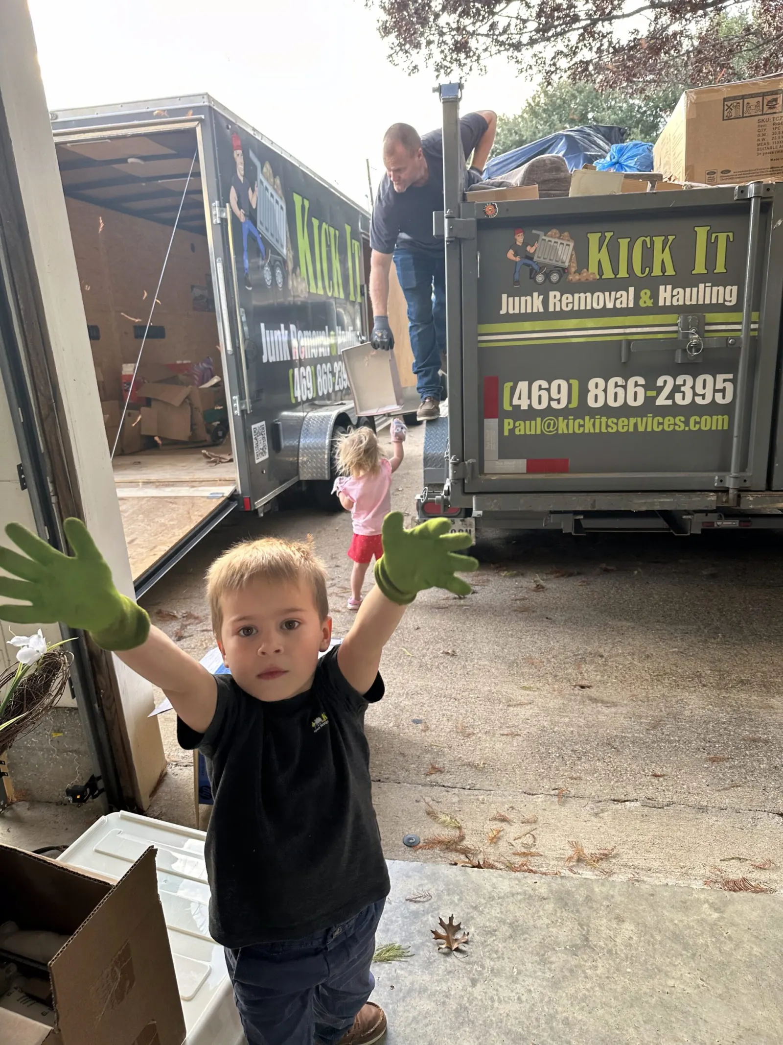 Kick It kid in work gloves beside the loaded dump trailer