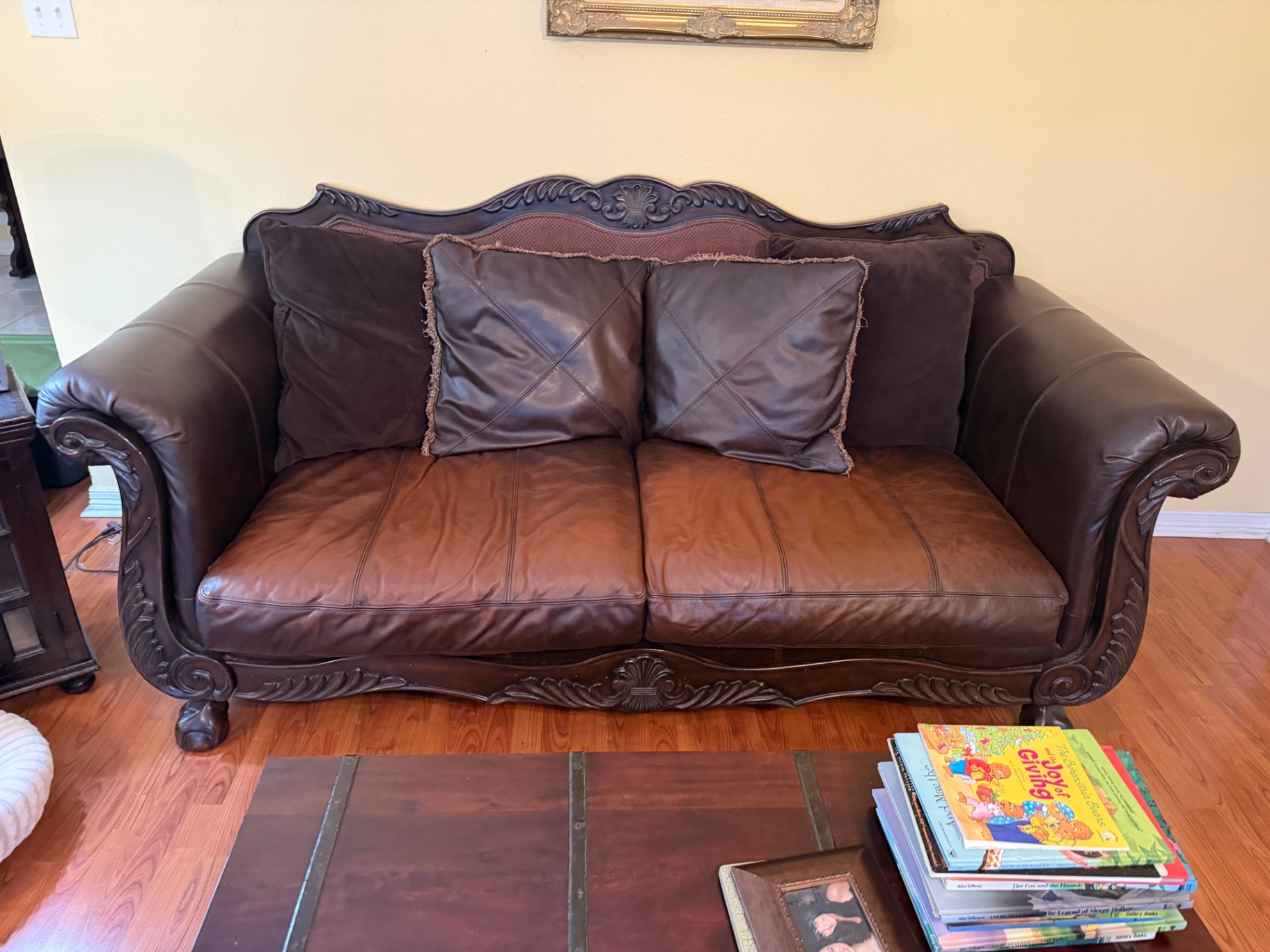 Brown leather couch with carved wood frame ready for removal
