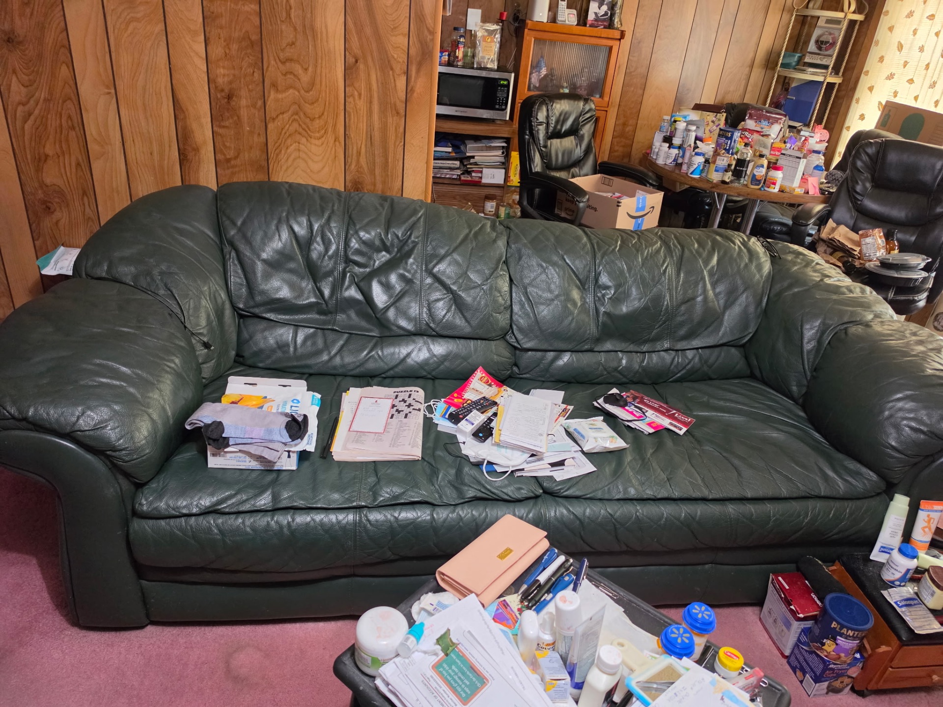 Green leather sofa in a cluttered room during a cleanout
