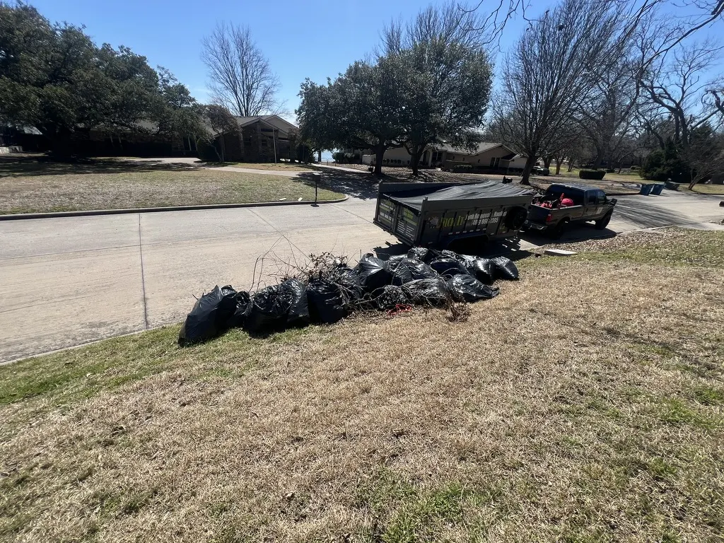 Bagged yard waste lined up for pickup beside the Kick It trailer